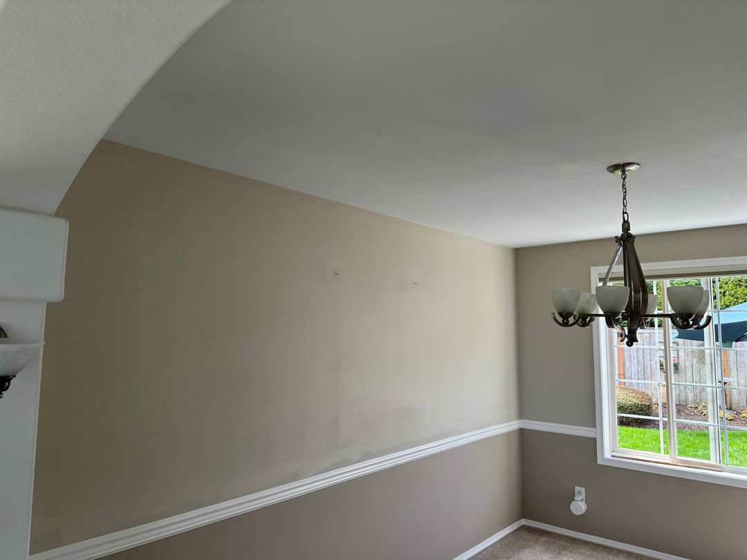 Painter feathering a color-matched blend so the patch disappears into the wall